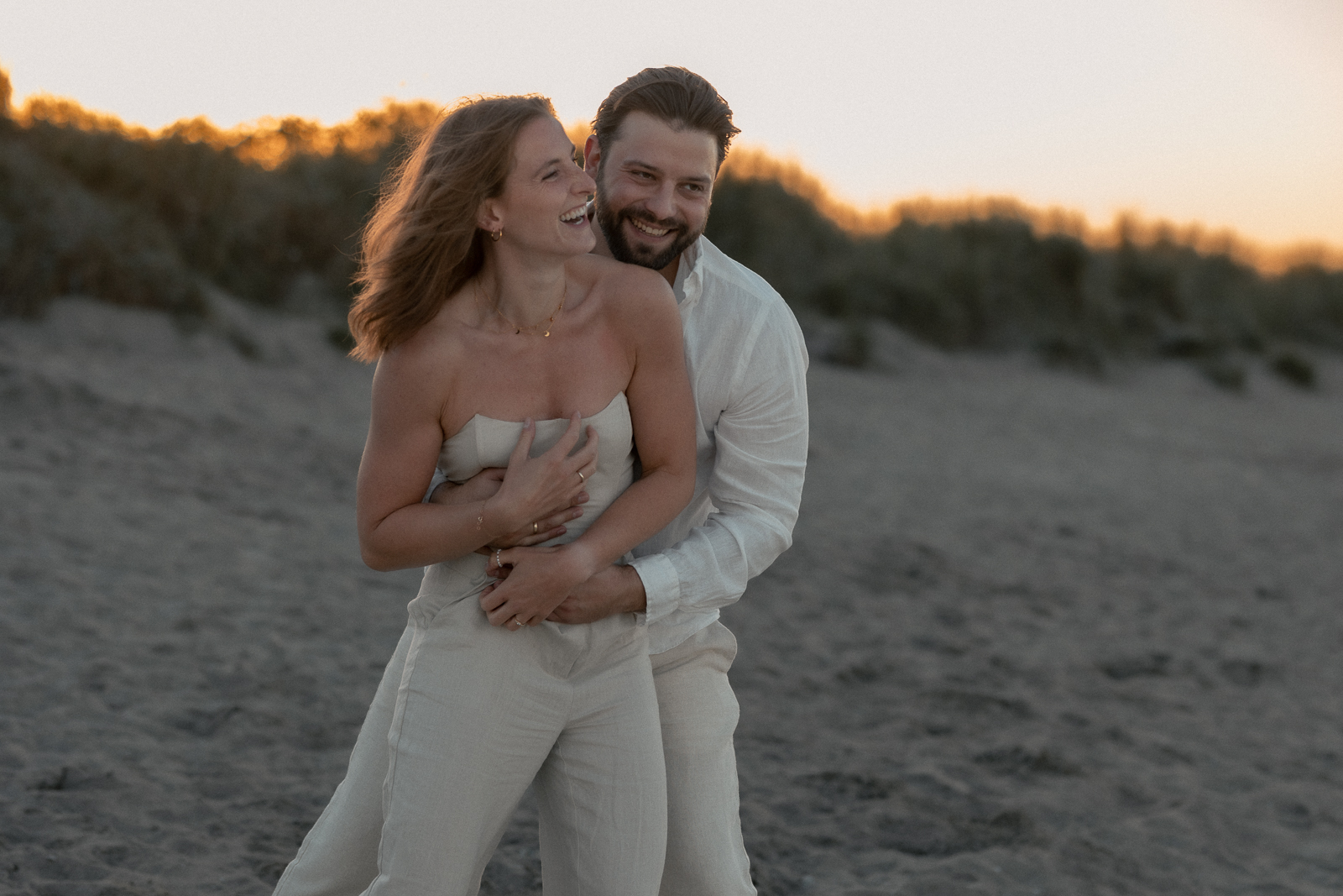 Paar lachend im Sonnenuntergang am Strand